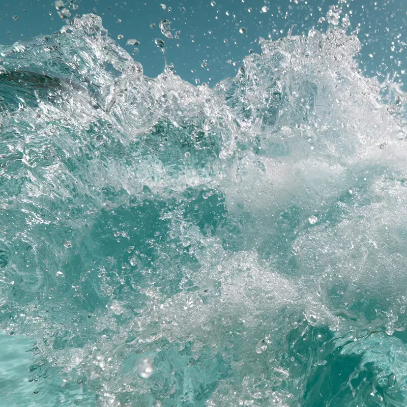 Close-up of clear blue ocean water splashing dynamically against the sky