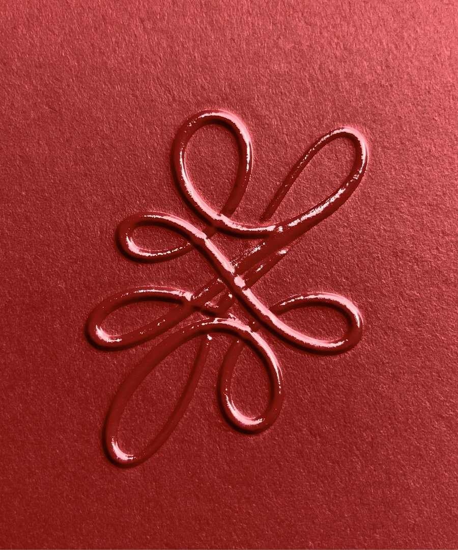 A shiny, raised swirl pattern created with a liquid medium on textured red paper