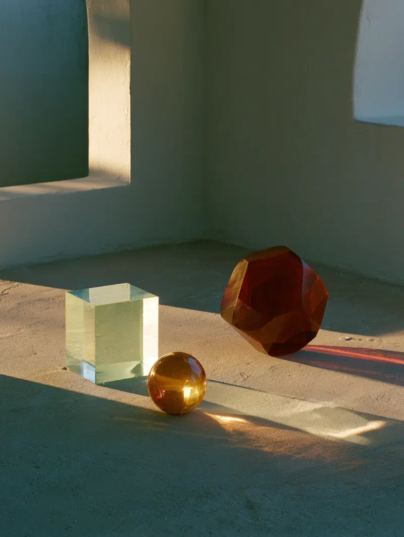 Artful photograph of glass and crystal geometric shapes casting shadows in warm sunlight