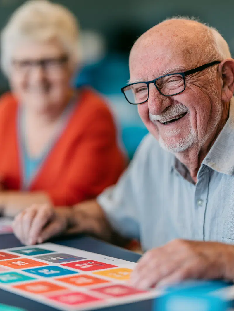 Joyful elderly man and woman enjoying a colorful board game together