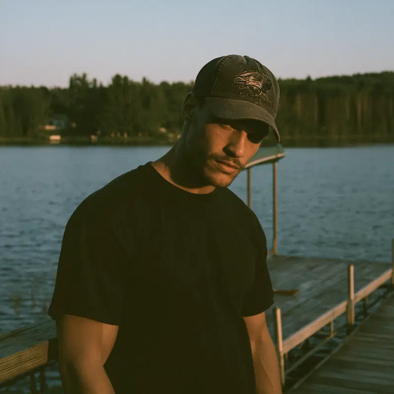 Portrait of a man wearing a baseball cap near a lake during golden hour