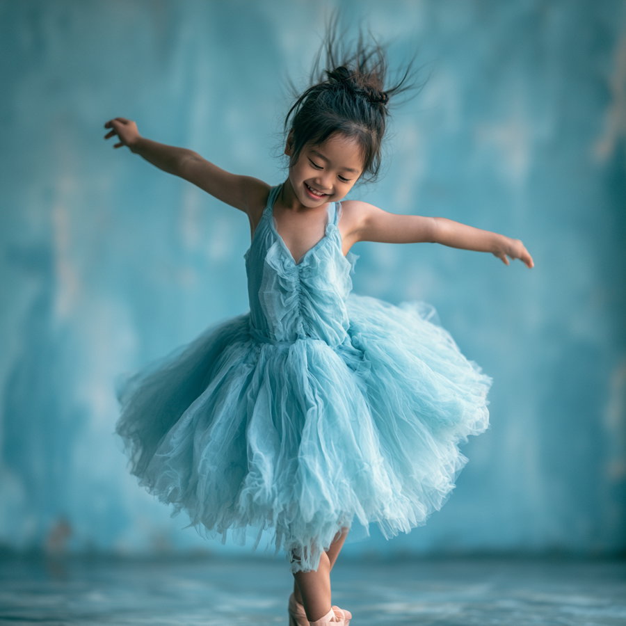 A young girl with a top knot hairstyle wearing a ruffled blue dress is spinning with arms outstretched and smiling against a similarly blue-toned background