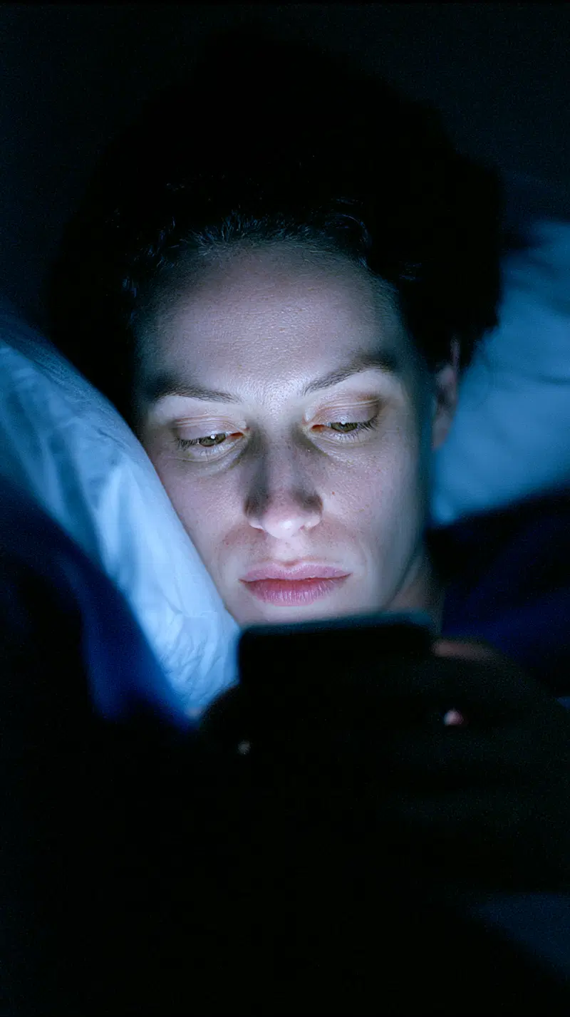 Portrait of a person illuminated by phone light in a dark room