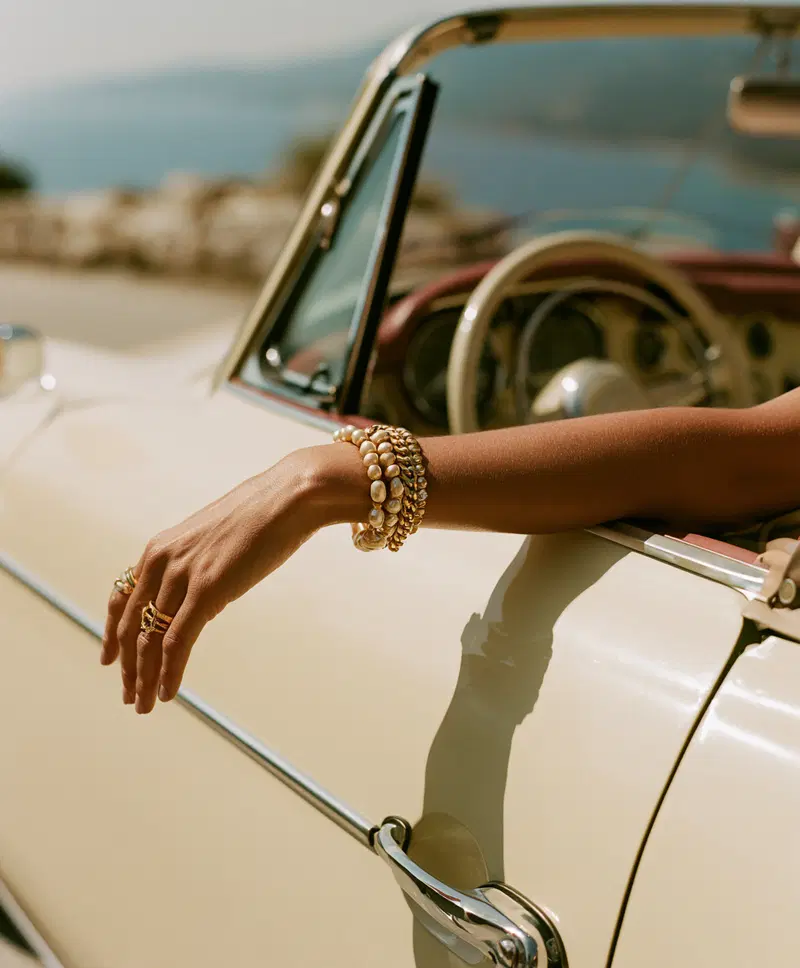 Close-up photography of a hand with jewelry resting on vintage car door