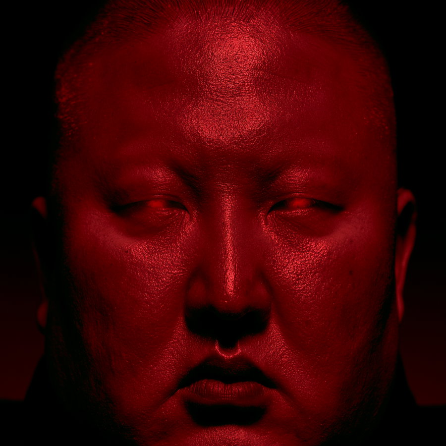 A close-up image of a person's face illuminated with red lighting, casting shadows and giving an eerie, intense atmosphere