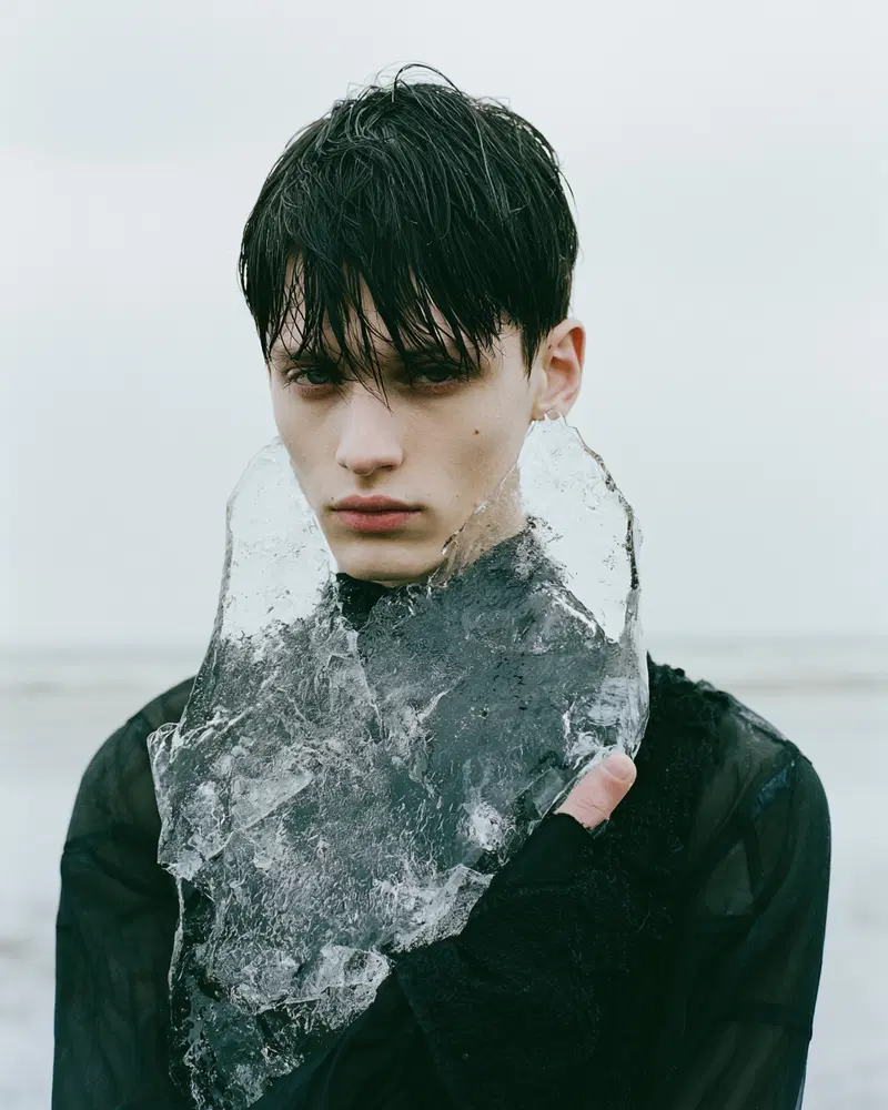 Portrait of a young man holding a large transparent ice piece against chest