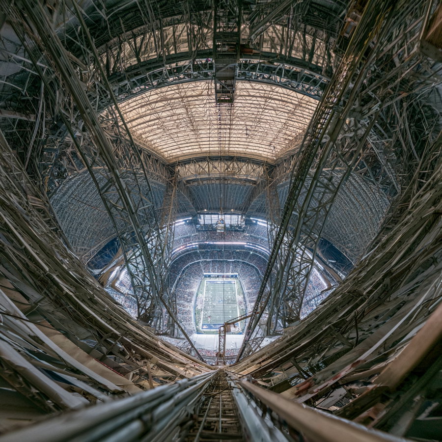 View from high inside a steel framework looking down at a football stadium filled with spectators
