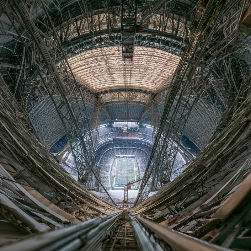 Inside view of a large steel-structured stadium with a football field