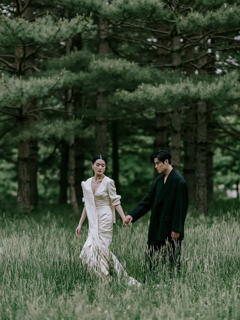 Elegant couple holding hands while walking in a lush green forest