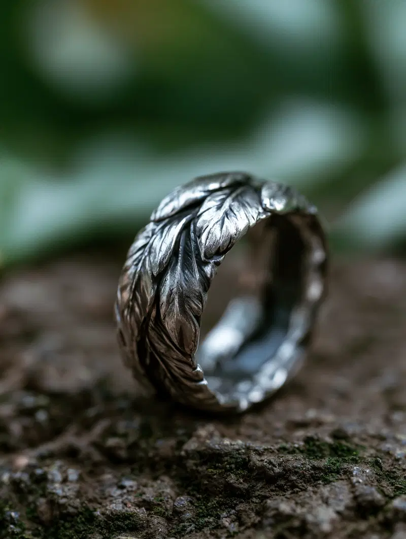 Close-up of a silver ring with intricate leaf design on a natural surface