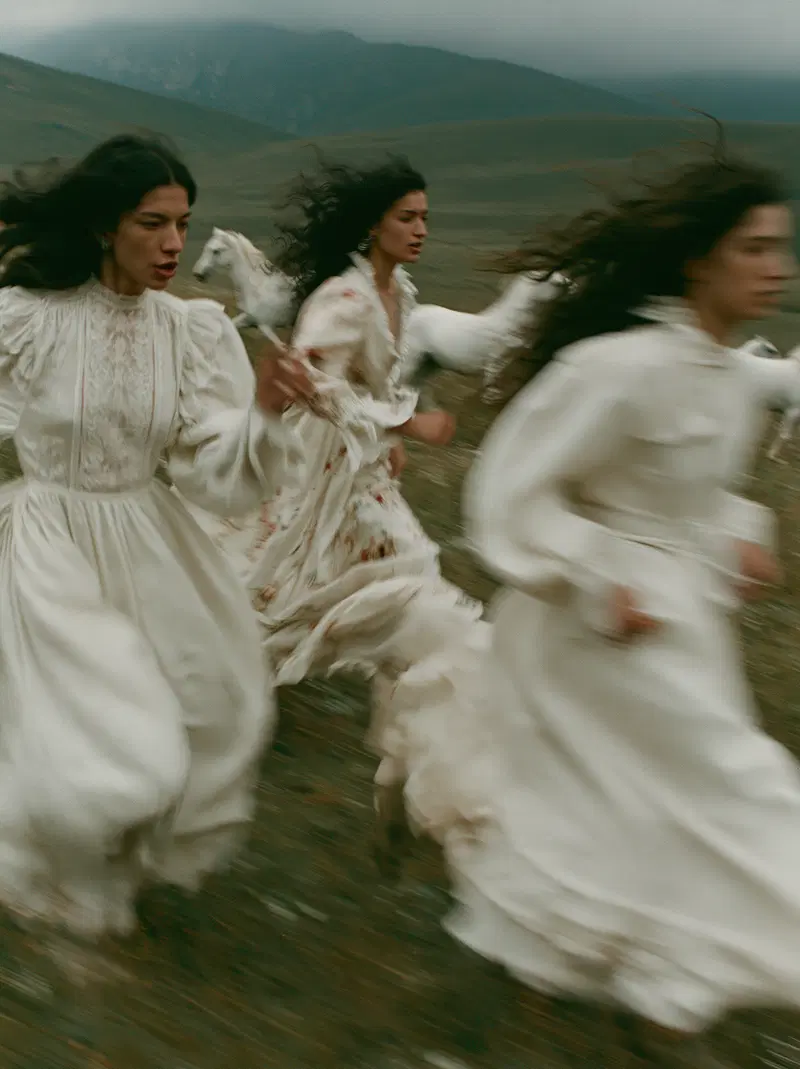 Fine art photograph of three women in vintage dresses running with white horses