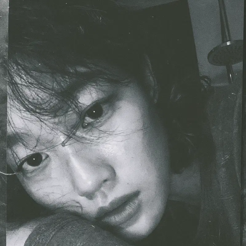 Close-up black and white photograph of a person's face with a contemplative expression