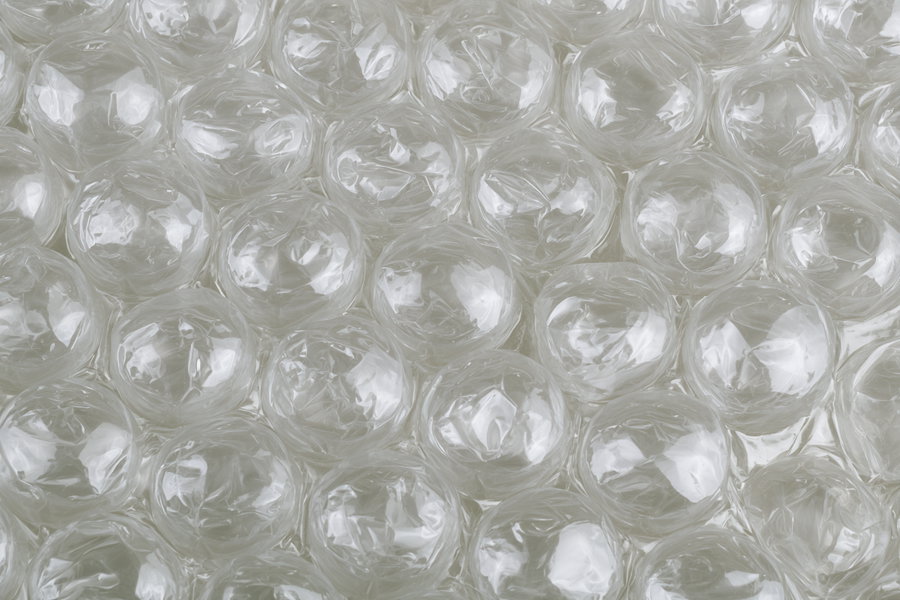 A close-up image showing a surface covered in transparent bubble wrap with light reflecting off the plastic bubbles.