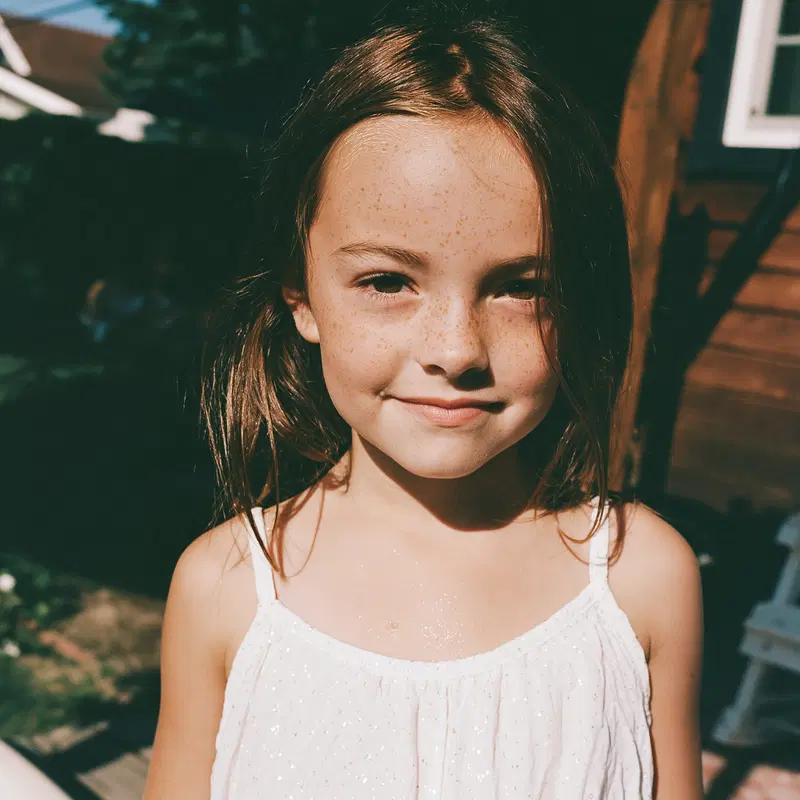 Portrait of a Girl with Freckles and Brown Hair Outdoors in Sunlight