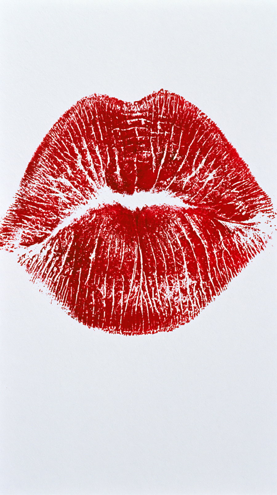 Close-up image of a red lipstick kiss mark on white paper showing lip texture and lines