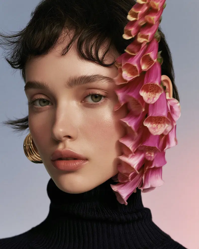 Close-up portrait of a woman with flowers next to her face and elegant gold earrings
