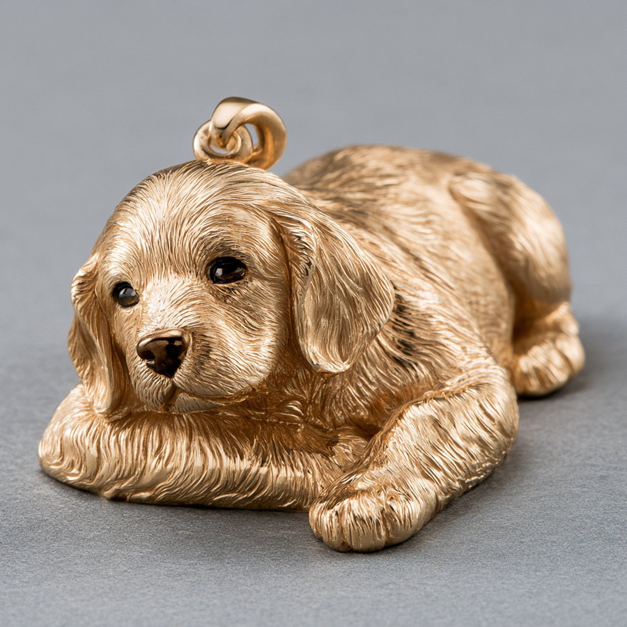 Gold pendant in the shape of a small puppy dog lying down with detailed fur and facial features on a gray background