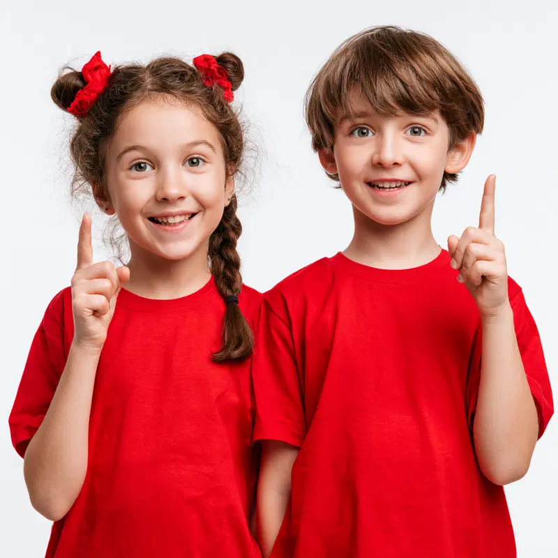 Smiling young girl and boy in red shirts pointing upward with joy