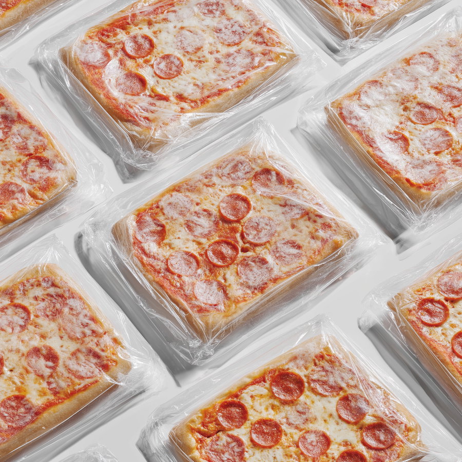 Frozen thin crust pizzas wrapped in plastic on white background