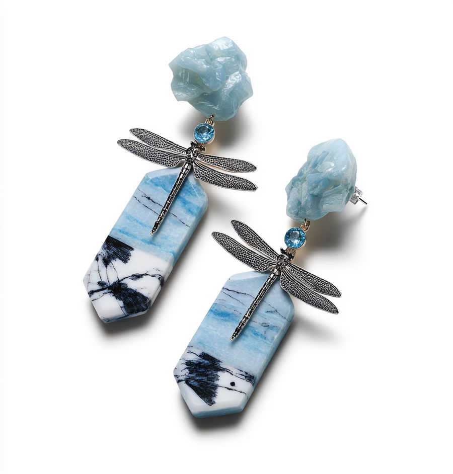 Geometric earrings with blue topaz and dragonfly pattern above aquamarine statue
