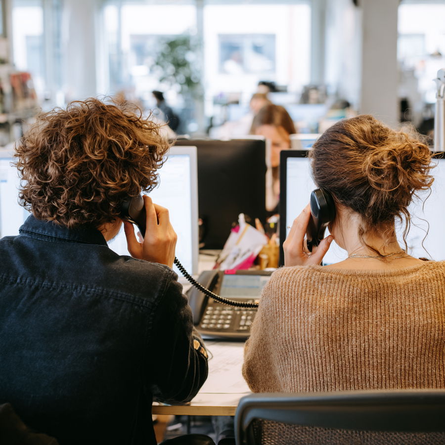 Two coworkers making phone calls in a modern office