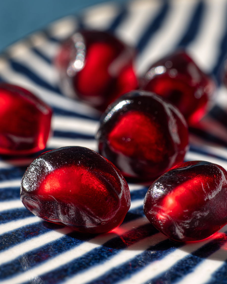 Sparkling pomegranate seeds on striped ceramic surface