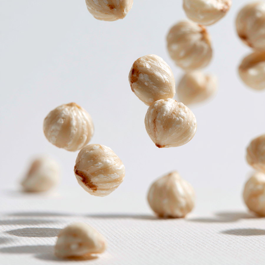 Close-up of white, textured snack items suspended in air against a light background, with some items on the surface below.