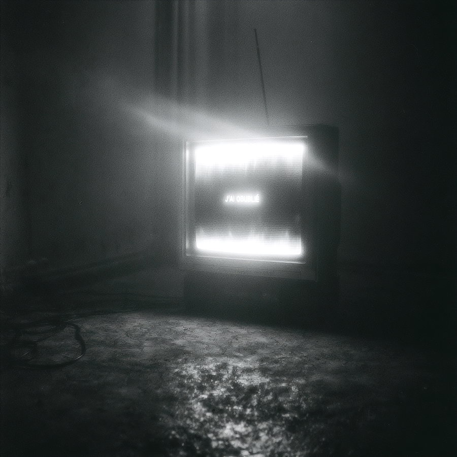 A vintage television set emitting a bright, glowing display in a dark, atmospheric setting, with shadows and textures on the floor.