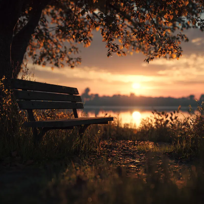 Serene lakeside scene with an empty wooden bench at sunset